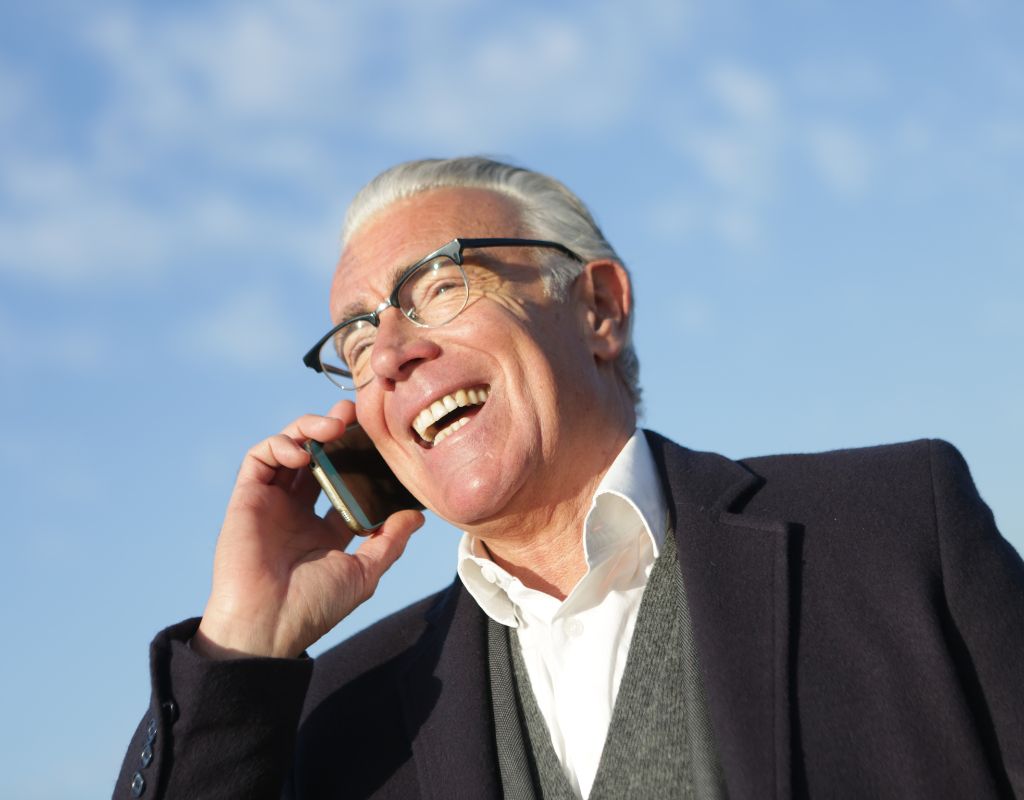 hombre mayor sonriendo y hablando por teléfono