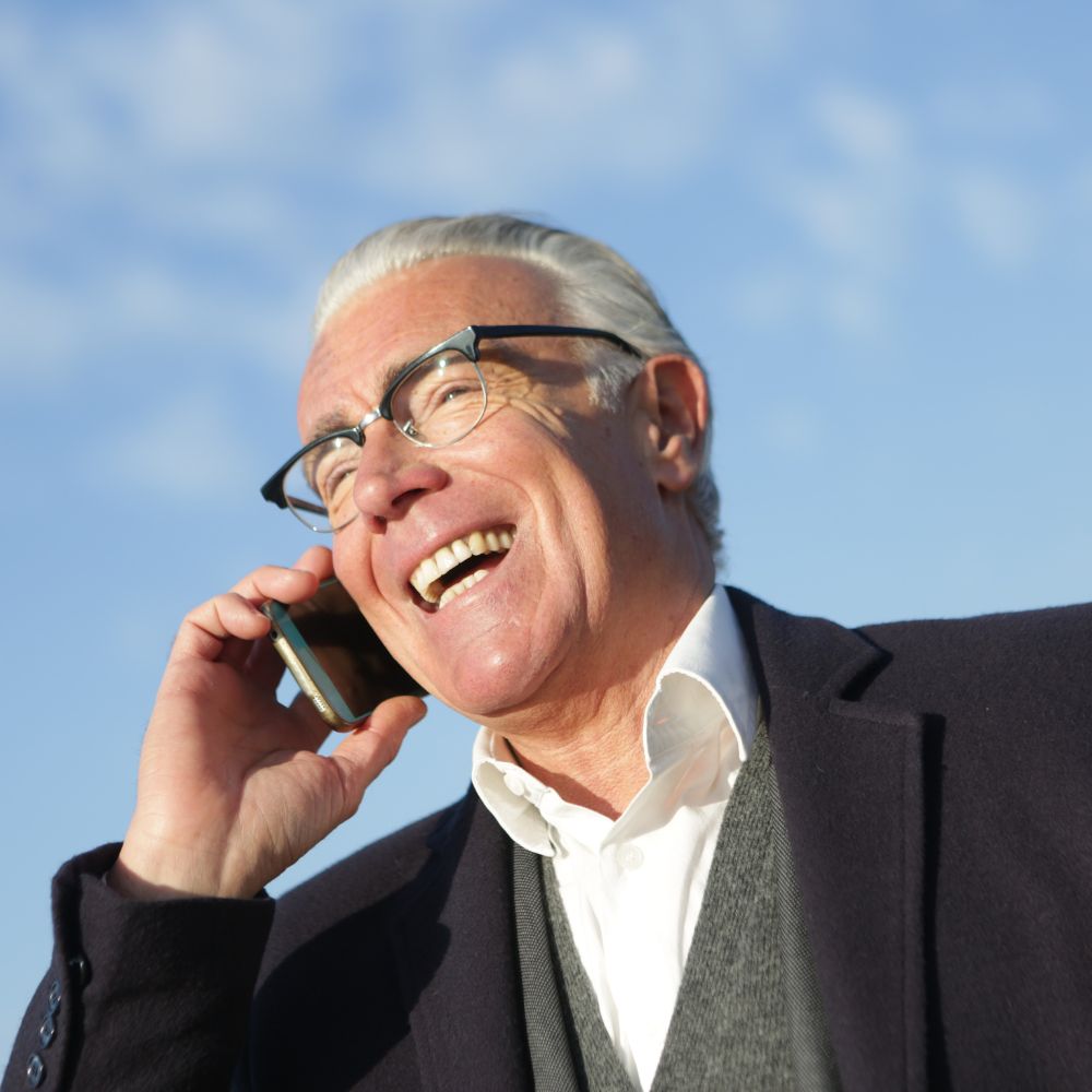 hombre mayor sonriendo y hablando por teléfono