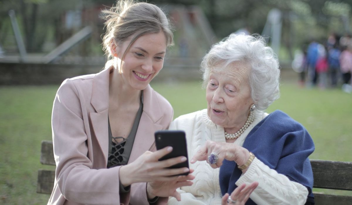 mujer y persona mayor comunicandose y pasando tiempo juntas con un smartphone